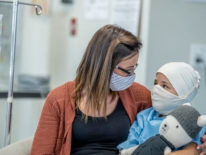 Un niño con cáncer de nueve años sentado junto a su madre en el hospital.