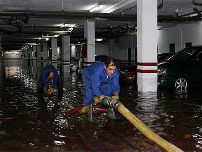 Dos trabajadores intentaban ayer achicar agua de un sótano inundado en Córdoba.