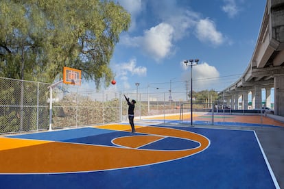 A young man plays basketball on one of the park's courts.