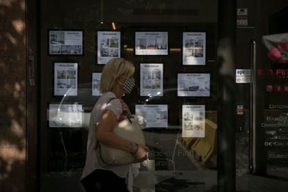 Una mujer pasea delante de una agencia inmobiliaria en el barrio del Eixample en Barcelona.