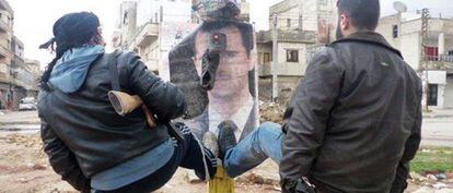 Rebeldes sirios derriban un cartel con el retrato de Bachar el Asad.