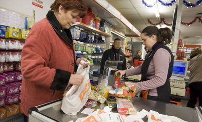 Una mujer y la cajera de un supermercado, meten la compra en bolsas de pl&aacute;stico. 