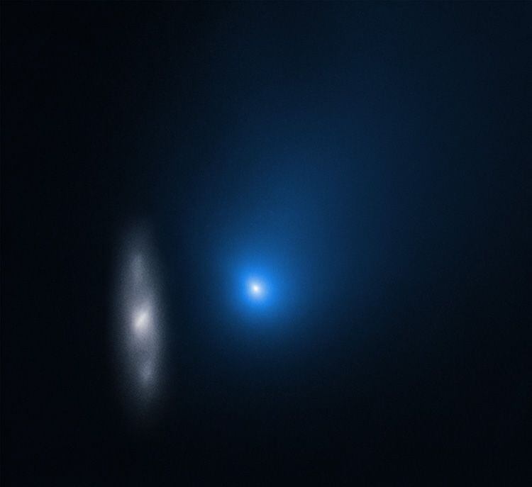 2I/Borisov aparece como un punto azul borroso frente a una galaxia espiral distante (izquierda) en esta imagen de noviembre de 2019, tomada por el telescopio espacial Hubble, cuando el objeto estaba aproximadamente a unos 322 millones de kilómetros de la Tierra.