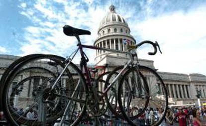 Transeúntes caminan cerca de dos bicicletas puestas sobre el techo de un carro en La Habana. EFE/Archivo