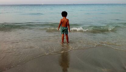 Un nen a punt de banyar-se en una platja.