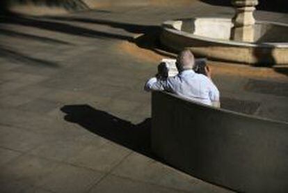 Un pensionista lee el peri&oacute;dico en una plaza de Sevilla.