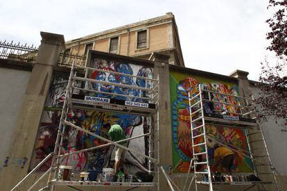Dos artistas gr&aacute;ficos pintan los muros externos del espacio autogestionado de Tabacalera. 