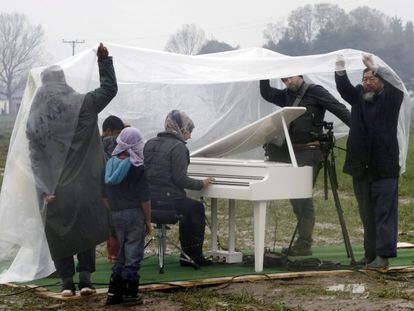 El artista Ai Weiwei (derecha) asiste a la actuaci&oacute;n de piano de la siria Nour Al Khizam en el campo de refugiados situado en la frontera entre Grecia y Macedonia el pasado 12 de marzo. 