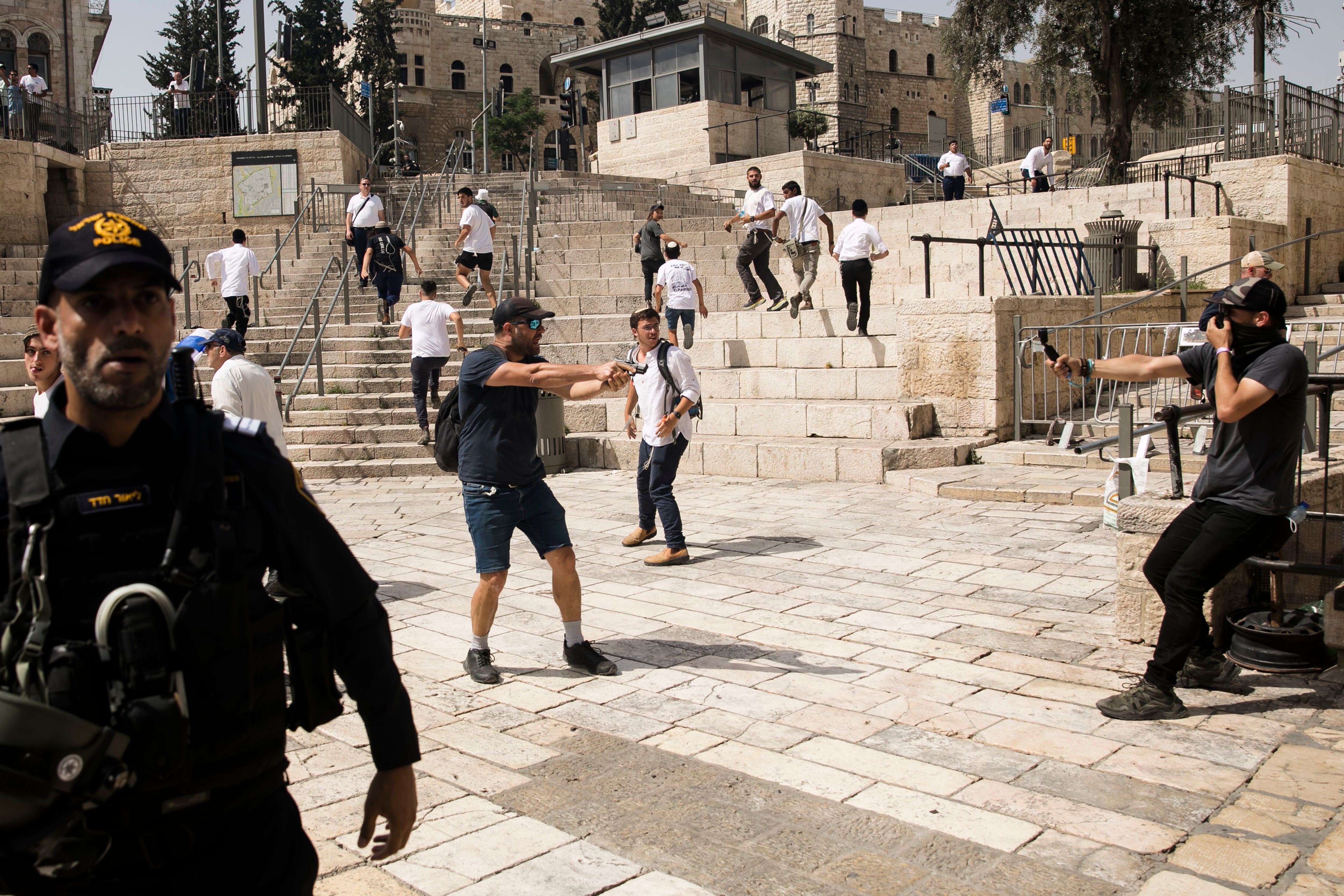 Un hombre israelí apunta con una pistola durante la marcha por el barrio musulmán de la Ciudad Vieja de Jerusalén.