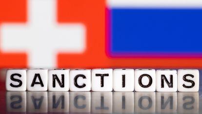 Letras que forman la palabra "sanciones", con una bandera suiza y la rusa al fondo.