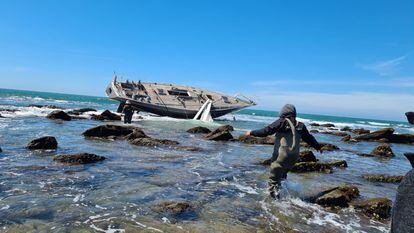 Unas personas se acercan al velero 'Capitán III' embarrancado en el arrecife de Salmedina, Cádiz.