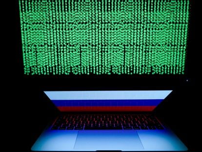 Un código digital en una pantalla ante un ordenador portátil con una bandera de Rusia.