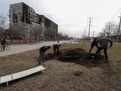 Un grupo de hombres cava una fosa para enterrar a víctimas mortales del ataque a Mariupol, el domingo.