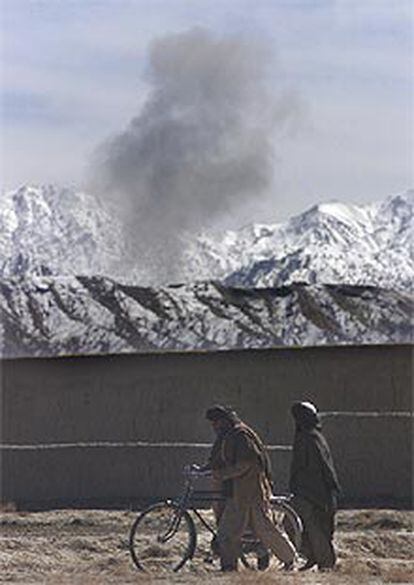 Varios civiles afganos pasean mientras las bombas caen en las montañas de Surmad.
