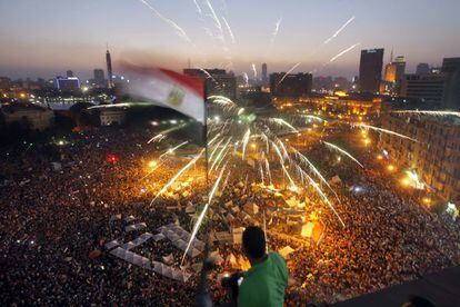 Fuegos artificiales en la plaza de Tahrir mientras un opositor de Morsi ondea una bandera egipcia, una imagen que se est&aacute; volviendo ya cl&aacute;sica. 