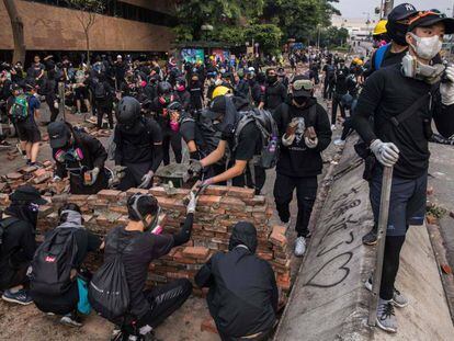 Manifestantes construyen este jueves un muro de ladrillo para cortar una calle junto a la Universidad Politécnica de Hong Kong.