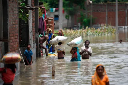 Habitantes de India caminan por una calle inundada cargando con sus pertenencias tras las intensas lluvias monzónicas en el distrito de Sitamarhi, en el estado indio de Bihar, el 17 de julio de 2019.