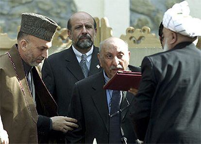 El presidente de la comisión constitucional (derecha) entrega el borrador al ex rey Mohammad Zahir Shah (centro) en presencia del  presidente Karzai (izquierda).