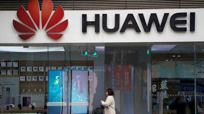 Una mujer camino frente a una tienda de Huawei en Shánghai.