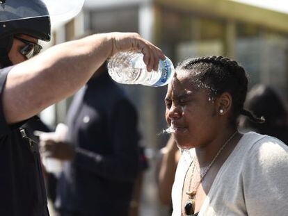 Un polic&iacute;a lava la cara de una mujer que fue alcanzada por spray de pimienta, ayer en Baltimore. 