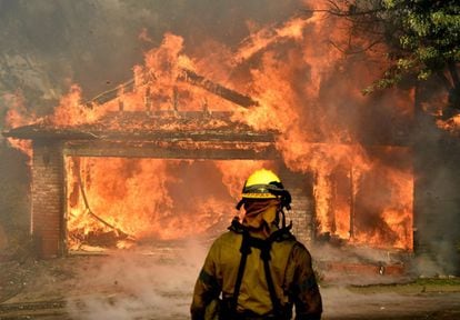 Los bomberos intentan salvar una de muchas casas incendiadas por el fuego ocasionado por los fuertes vientos en Kagel Canyon en San Fernando Valley, California. 