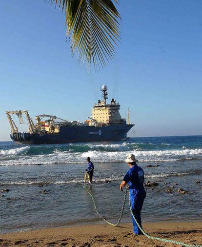 Obreros cubanos arrastran un cable submarino de fibra óptica en la playa de Siboney.