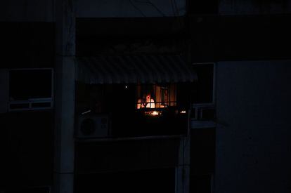 Un hombre utiliza una vela para iluminar la sala de su casa en un edificio afectado por el apagón eléctrico nacional, este martes. Durante el episodio pasado de la falla eléctrica en Venezuela, hubo más de 300 establecimientos saqueados en la ciudad de Maracaibo, probablemente la más afectada por el desgobierno reflejado durante esa crisis.