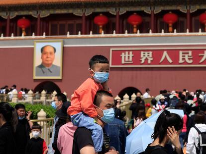 Un hombre y un niño con mascarillas visitan la entrada a la Ciudad Prohibida, en Pekín.
