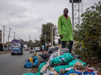 Evans Otieno posa encima de plásticos y basura en descomposición en el asentamiento chabolista de Dandora, Nairobi.