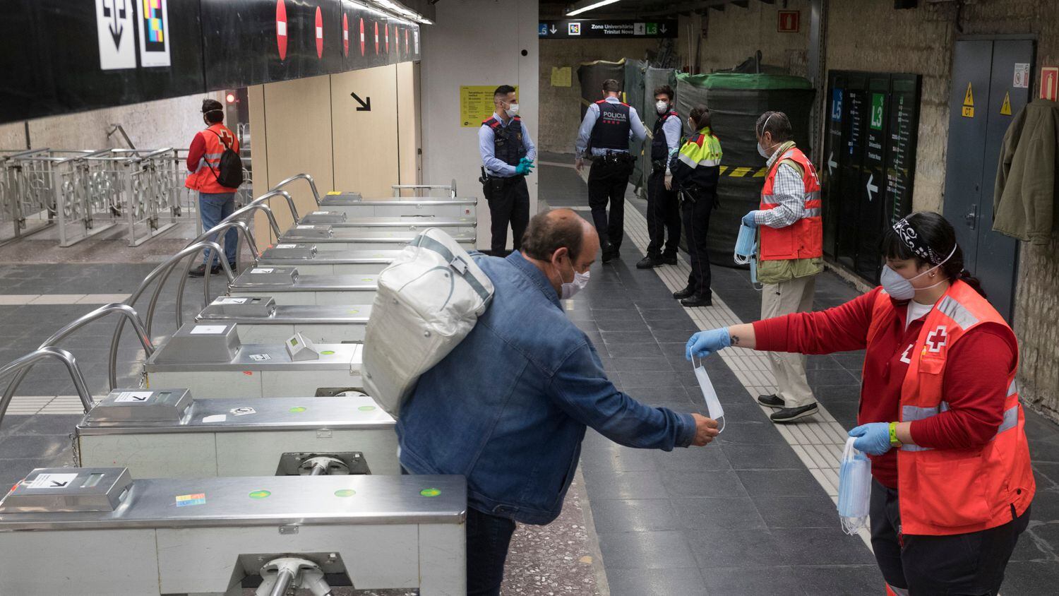 Voluntarios de Protección Civil y de Cruz Roja reparten mascarillas en el Metro de Barcelona.