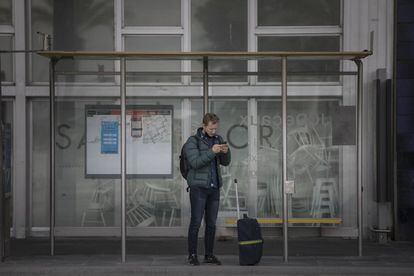 Un turista espera l'arribada del bus en una parada de la Terminal 2 de l'aeroport del Prat. Quan ha arribat a la terminal ha comprovat que no està en funcionament.