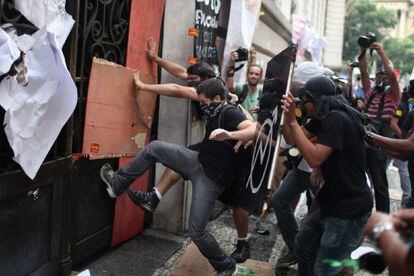 Manifestantes intentan romper una puerta de acceso ayer, martes, durante los disturbios en R&iacute;o de Janeiro.