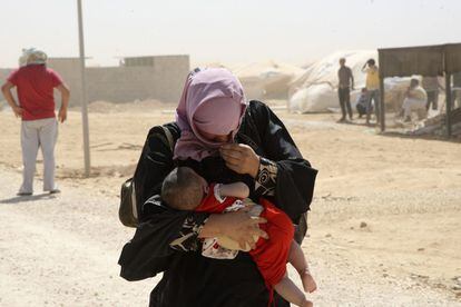 Una refugiada siria lleva a su hijo en brazos mientras camina entre una tormenta de arena en el campo de refugiados de Al Zaatr, en Mafraq (Jordania), cerca de la frontera con Siria, donde se desarrolla una guerra civil. Agosto 2012.