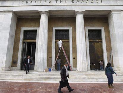 Varias personas pasan delante de la sede del Banco de Grecia. 
