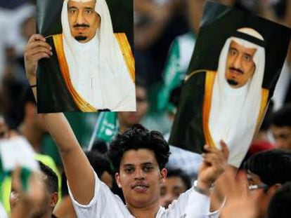 Seguidores de Arabia Saud&iacute; sostienen fotos del rey Salman bin Abdulaziz durante un partido de f&uacute;tbol en Yeda.