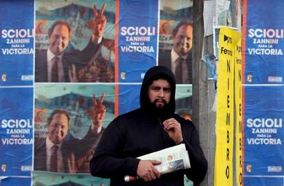 Un hombre espera el autobús frente a la propaganda de Scioli.
