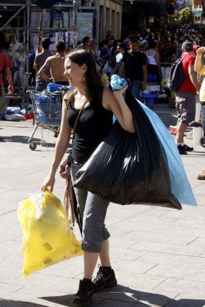 Una joven ayuda a los servicios de limpieza a recoger algunos restos tras la acampada de Sol.