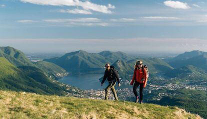 Una pareja de senderistas con el lago de Lugano como telón de fondo.
