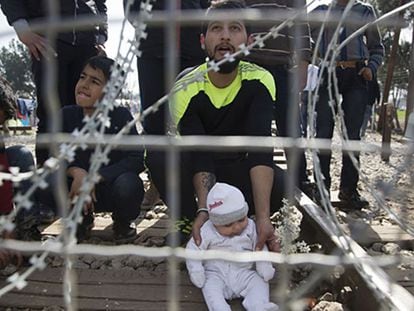 Pie de Foto: Un hombre espera junto a su hijo en la frontera griega con Macedonia, este martes.