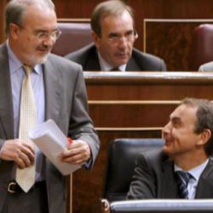 Pedro Solbes conversa con Rodríguez Zapatero mientras se dirige al estrado del Congreso.