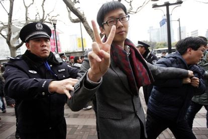Un hombre arrestado por la policía hace la señal de la victoria en el lugar donde estaba convocada una protesta en Shanghái.