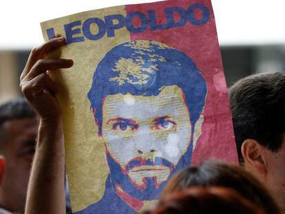 Un partidario de Leopoldo L&oacute;pez muestra un cartel con su rostro a las puertas de un tribunal de Caracas, el 20 de junio