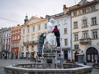 Dos operarios protegen una de las estatuas del centro de Lviv para evitar que sufran daños ante un ataque ruso, en el octavo día desde el inicio de la guerra en Ucrania.