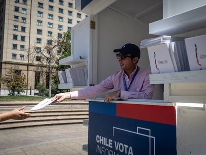 Un hombre entrega un ejemplar del borrador de la nueva Constitución, en una caseta frente al Palacio de La Moneda, en Santiago, el 13 de diciembre de 2023.