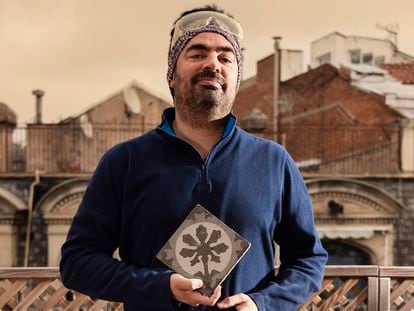 Joan Moliner sostiene en su casa una baldosa del año 1900 de la fábrica Escofet. Es un diseño de Enric Moyà. En la página siguiente, un catálogo de las piezas y la terraza-estudio de Moliner.