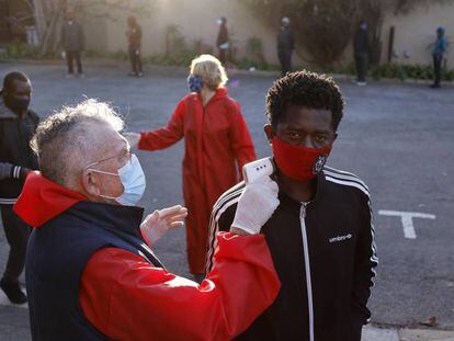 Un voluntario toma la temperatura en una cola durante el reparto de comida en  una iglesia de Johannesburgo (Sudáfrica). 