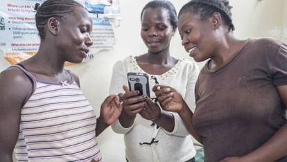 Tres mujeres miran un móvil, uno de los elementos que pueden ser fundamentales en los próximos años en la salud materna.