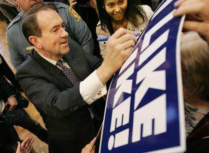 El aspirante republicano Mike Huckabee firma banderas con su nombre en la Universidad de Maryland.
