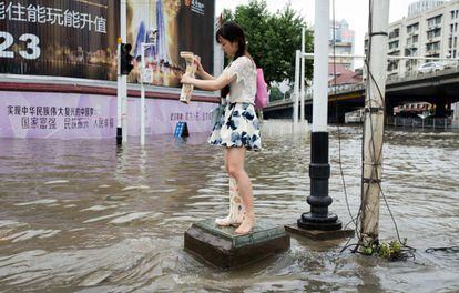 Una mujer vacía agua de sus botas en una calle inundada en Wuhan (China).