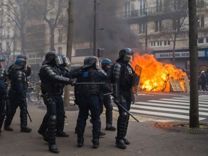 Policías antidisturbios cargan junto a una barricada que arde en la masiva manifestación, el jueves.
